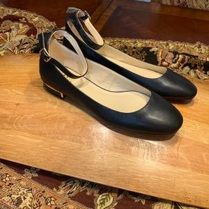 Vince Camuto - black leather flats with ankle strap. 1” heel . Gold look trim